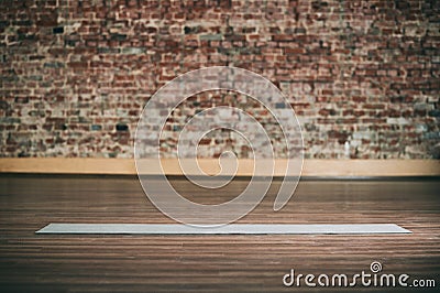 Empty space in fitness center, brick wall, natural wooden floor, modern loft studio, unrolled yoga mat on the floor. Stock Photo