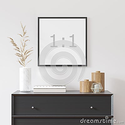 Empty square frame on white wall with black dresser, white vase and wood decor. Stock Photo