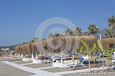 Empty sunbeds and gazebos with salt roofs on the beach in Turkey Stock Photo