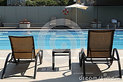 Empty sunbeds near outdoor swimming pool at resort Stock Photo