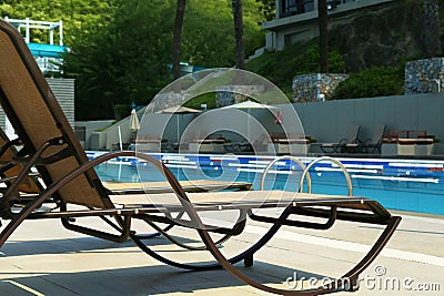 Empty sunbeds near outdoor swimming pool at resort Stock Photo
