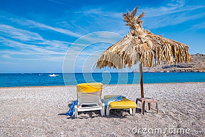 Empty sunbeds and umbrella on Vlycha beach near Lindos village Stock Photo