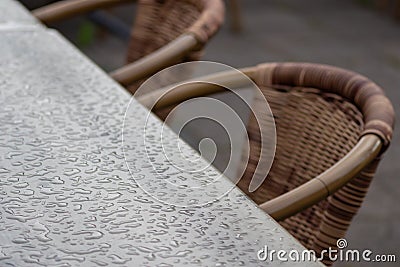 Empty table and empty chairs of summer restaurant or beer garden in summer on rainy day with raindrops and no guests, no income on Stock Photo