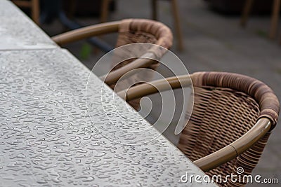 Empty table and empty chairs of summer restaurant or beer garden in summer on rainy day with raindrops and no guests, no income on Stock Photo