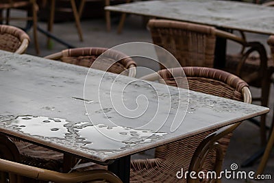 Empty table and empty chairs of summer restaurant or beer garden in summer on rainy day with raindrops and no guests, no income on Stock Photo