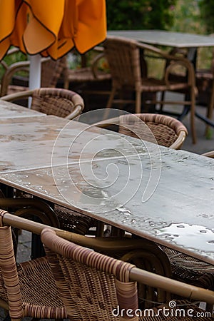 Empty table and empty chairs of summer restaurant or beer garden in summer on rainy day with raindrops and no guests, no income on Stock Photo