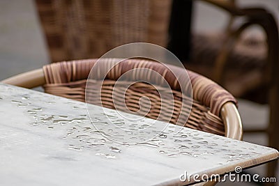 Empty table and empty chairs of summer restaurant or beer garden in summer on rainy day with raindrops and no guests, no income on Stock Photo