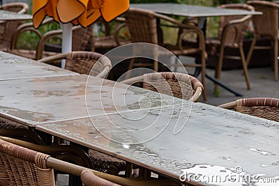 Empty table and empty chairs of summer restaurant or beer garden in summer on rainy day with raindrops and no guests, no income on Stock Photo