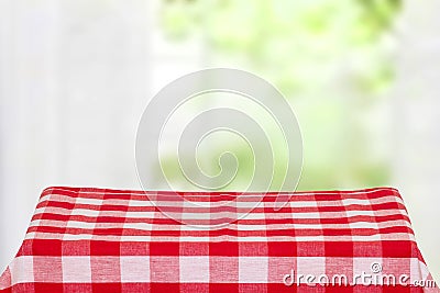 Empty table product. Closeup of a empty red checkered tablecloth or napkin on a rustic table against blurred curtains background. Stock Photo