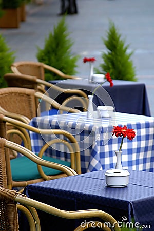 Empty tables on the street with roses on them outside a cafe bar or restaurant . Stock Photo