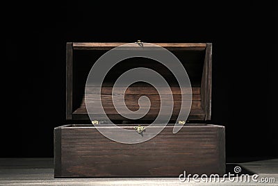 Empty treasure chest on wooden table against black background Stock Photo