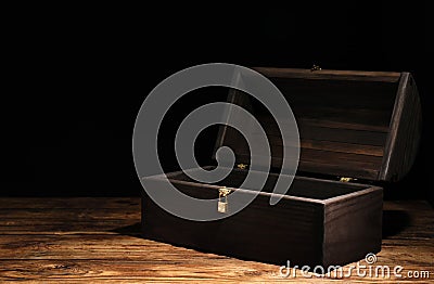 Empty treasure chest on wooden table against black background. Space for text Stock Photo