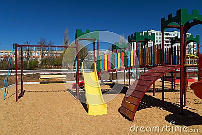 Empty urban residential infrastructure, nobody - children`s playground next to a condominium. Swing, slide, stairs, multistory Stock Photo