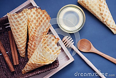 Empty waffle cones Homemade Dessert with wooden Accesories and honney. Blue Background. Top view Stock Photo