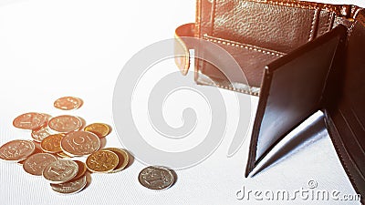 An empty wallet and some coins scattered next to it. Stock Photo