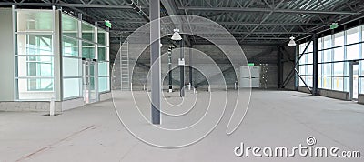 Empty warehouse with steel beams, glass windows and concrete walls. Stock Photo