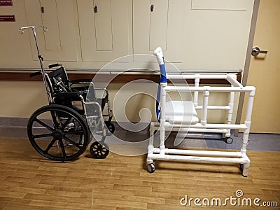 Empty wheelchair and bedside commode lined up in hospital hallway Stock Photo
