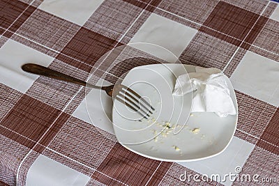 empty white dish with leftovers of eaten food, crumpled table-napkin and steel fork Stock Photo