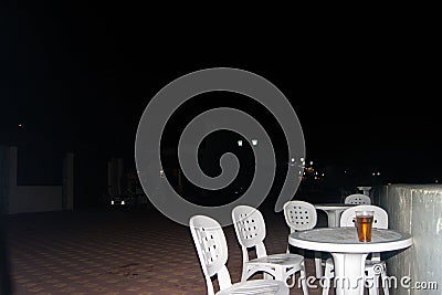 An empty white plastic summer table on the summer promenade, around a few chairs. Lunch party Stock Photo