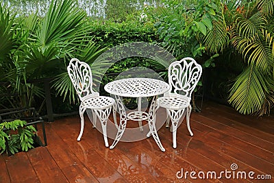 Empty white wrought iron garden tea table and chairs in the patio after rain Stock Photo