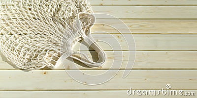 Empty wicker mesh bag on background of wooden tabletop made of sanded planks. White empty string bag Stock Photo