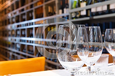Empty wine glasses on table close up with large group of bottles on shelf in background Stock Photo