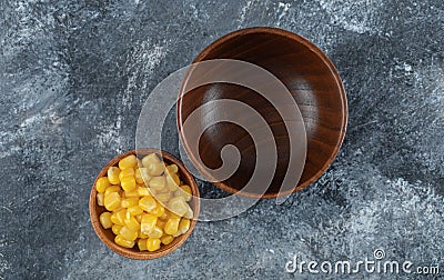 An empty wooden bowl with small bowl of popcorn seeds Stock Photo