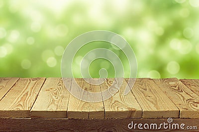 Empty wooden deck table with foliage bokeh background. Ready for product display montage. Stock Photo