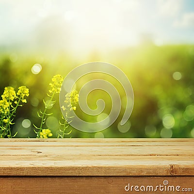 Empty wooden deck table over green meadow bokeh background for product montage display. Spring or summer season Stock Photo