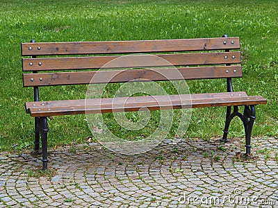 empty wooden iron bench on the park - grass and pavement background Stock Photo