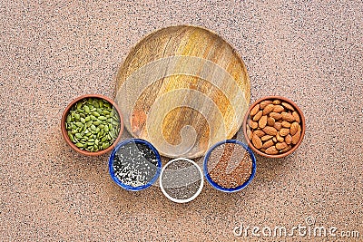 Empty wooden plate and semicircular frame various seeds in a bowl on a brown stone background. Seeds of flax, chia, pumpkin, Stock Photo