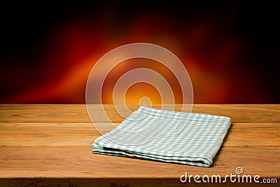 Empty wooden table with checked tablecloth over blur fire background. Stock Photo