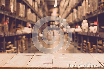 Empty wooden table on defocuced blurred boxes on rows of shelves Stock Photo