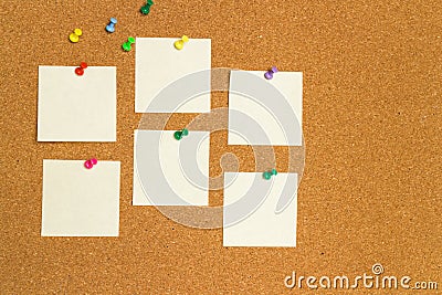 Empty yellow sticky notes on cork board with color pins Stock Photo