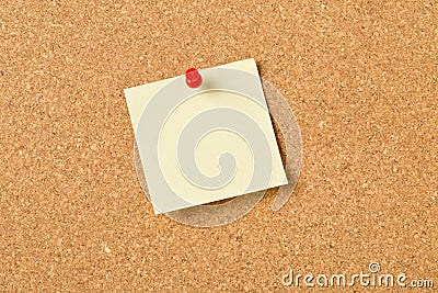 Empty yellow sticky paper memo note with red pin on cork board Stock Photo