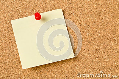 Empty yellow sticky paper memo note with red pin on cork board Stock Photo