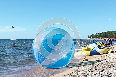 Empty zorb on the inshore waves, water activities, Zorbing extreme attraction for beach vacationers Editorial Stock Photo