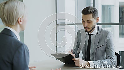 Encargado de sexo masculino de la hora que tiene entrevista de trabajo con la mujer joven en traje y que mira su uso del curricul almacen de video Encargado de sexo masculino de la hora que tiene entrevista de trabajo con la mujer joven en traje y que mira su uso del curricul almacen de video