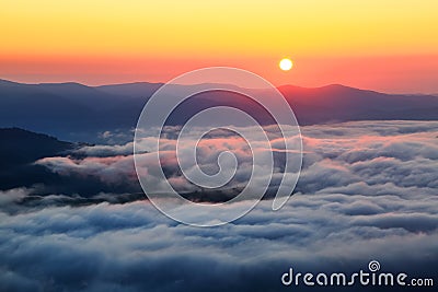 Enchanting sunrise at the high mountains, and at the bottom there is textured thick fog. Stock Photo