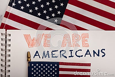 Encouraging patriotic message We Are Americans on white paper American flags in background Stock Photo