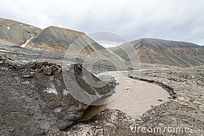 The end of the glacier. A brown river, the meltwater from the Longyear Glacier, coming from under the ice. Longyear Stock Photo