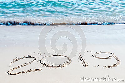 End of 2019 handwritten on the sandy beach with ocean wave washing away with water. Stock Photo