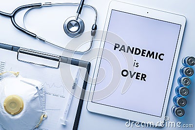 End of pandemic. Syringe with needle, hospital healthcare charts, doctor stethoscope and white tablet with text on Stock Photo