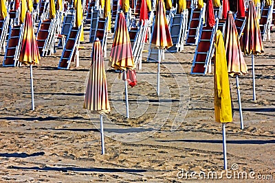 End of summer - Parasols and sun loungers closed on the beach Stock Photo