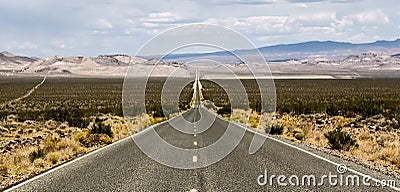 Endless empty road scenic landscape with a desert and mountains in the background in Nevada Stock Photo