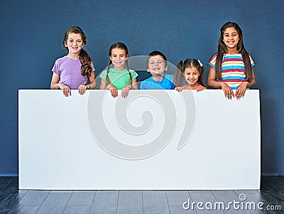 Endorsed by kids for kids. Studio shot of a diverse group of kids standing behind a large blank banner against a blue Stock Photo