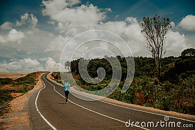 Endurance runner running on asphalt road in African nature. Marathon training in Kenya Editorial Stock Photo