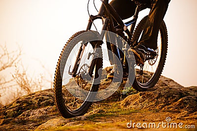 Enduro Cyclist Riding the Bike Down Rocky Hill at Sunset. Close up Extreme Sport Concept. Space for Text. Stock Photo