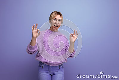 energetic cute blond woman in lavender sweater on purple background with copy space Stock Photo