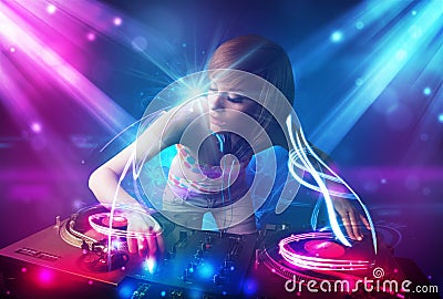 Energetic Dj girl mixing music with powerful light effects Stock Photo